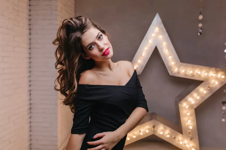 attractive curly woman stylish festive dress playing with hair against wall glowing star 197531 8139